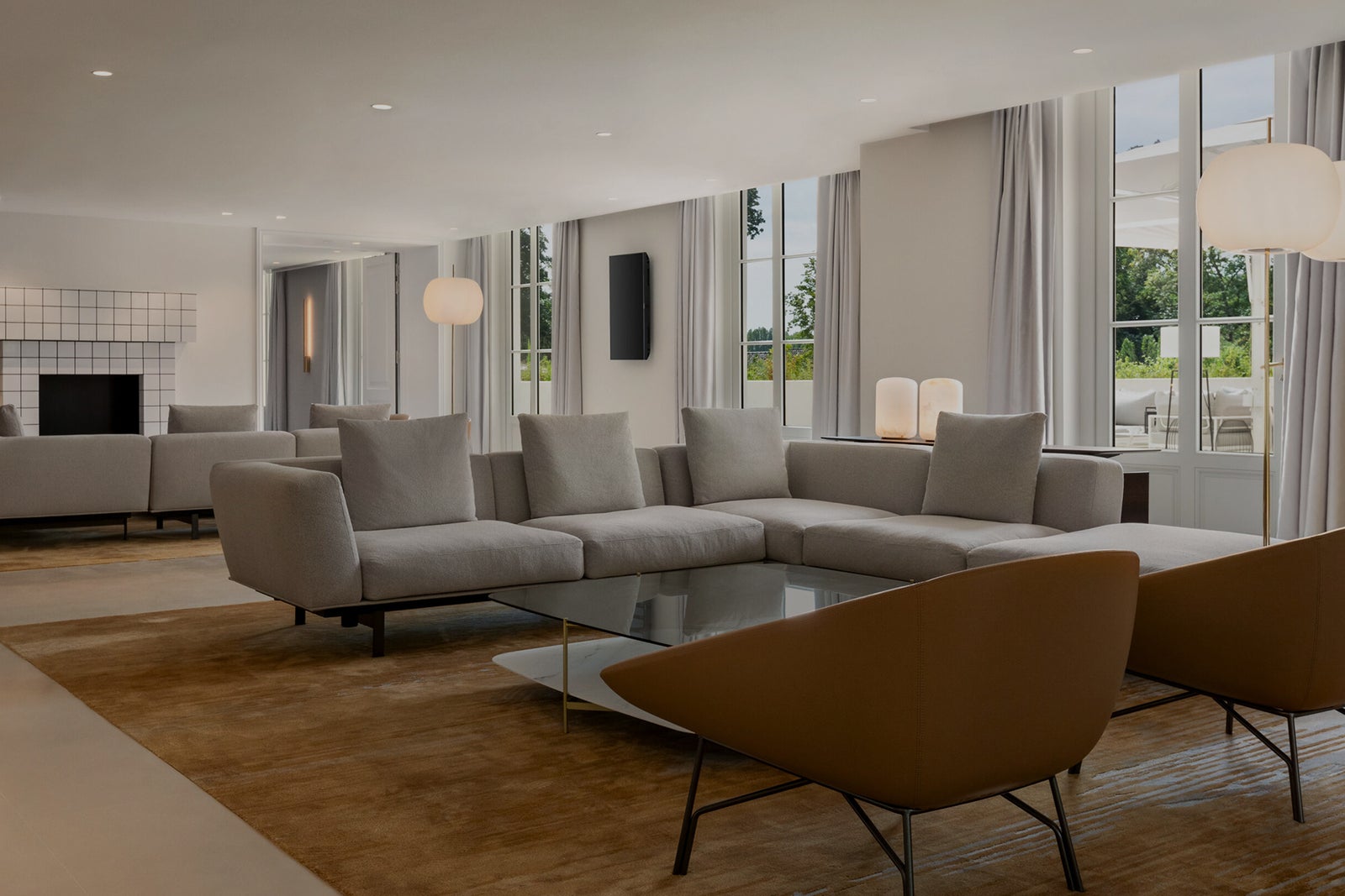 Bright hotel lobby with modern seating, tables, large windows and neutral-toned decor 