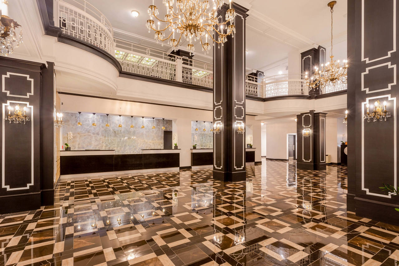 Grand hotel lobby with crystal drop lighting, marble floors, and dark oak columns. 