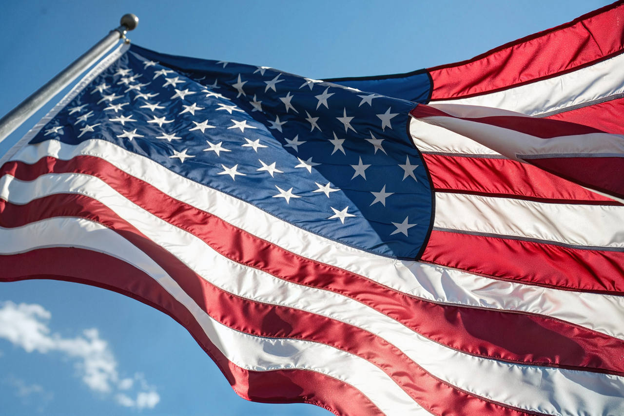 Close up image of the american flag blowing in the wind against a clear blue sky