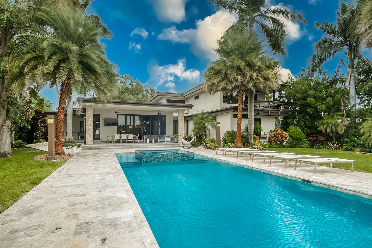 Closeup of a luxurious pool leading up to a hotel bar and palm trees.